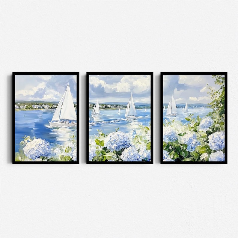 May include: Set of three framed art prints depicting sailboats on a blue sea under a cloudy sky. The artwork features white sailboats, blue water, and white and blue hydrangea flowers in the foreground. The frames are black.