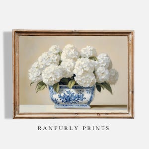 Pode incluir: Pintura emoldurada de hortênsias brancas em um vaso de porcelana azul e branco. A pintura tem um fundo bege claro e uma moldura de madeira marrom. O texto "RANFURLY PRINTS" está na parte inferior.