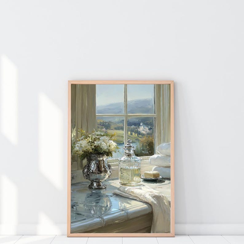 May include: A framed painting of a bathroom scene with a window overlooking a landscape. A silver vase with white flowers, a glass bottle, and a stack of white towels are on a tiled surface. A bar of soap sits on a small plate.