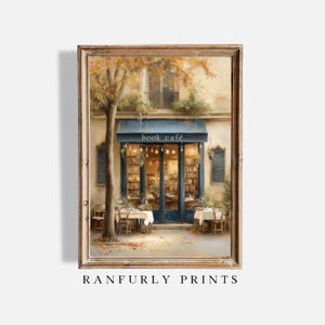 Könnte beinhalten: Gerahmter Kunstdruck eines Buchcafés mit blauem Vordach und der Aufschrift "book café". Tische und Stühle stehen draußen. Der Druck stammt von Ranfurly Prints.