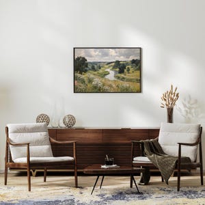 May include: A living room scene featuring two wooden armchairs with cream-colored cushions, a dark wood cabinet, and a small coffee table. A framed landscape painting hangs above the cabinet. Decorative spheres and a vase with dried plants add to the decor.