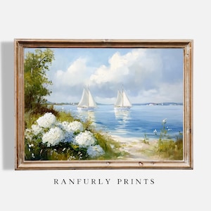 Op de afbeelding: Een ingelijst schilderij van een zeegezicht met twee zeilboten in de verte. Op de voorgrond staan witte hortensia's en groen gebladerte.