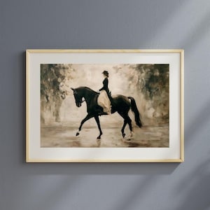 May include: Framed artwork depicting a person riding a black horse in a sepia-toned outdoor scene. The rider is dressed in a dark outfit with a light-colored skirt. The artwork is in a light-colored wooden frame, suitable for home decor.
