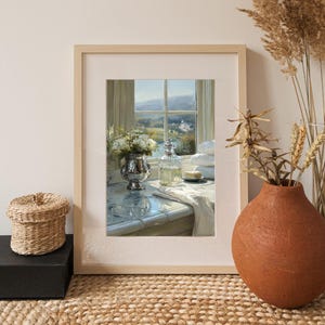 May include: A framed print of a still life scene. A silver vase with white flowers sits next to a clear glass bottle and a stack of white towels. The window in the background shows a landscape with a river and a building.