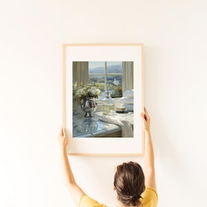 May include: A framed painting of a bathroom scene with a window overlooking a landscape. A silver vase with white flowers, a glass bottle, and a stack of white towels are on a marble countertop.