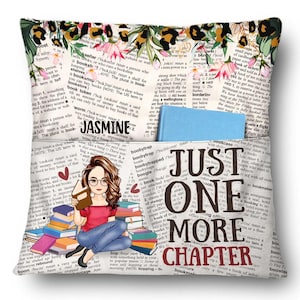 Op de afbeelding: Een decoratief kussen met een bloemen- en luipaardprintrand, met een ontwerp met boeken als thema. Het kussen heeft een zak en een illustratie van een vrouw die leest. De tekst op het kussen luidt "Jasmine" en "Just One More Chapter."