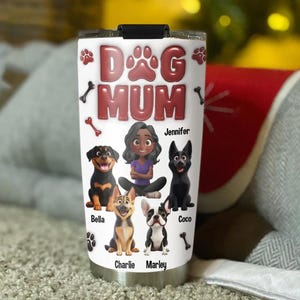 Op de afbeelding: Een witte beker met een rood "Dog Mum"-ontwerp. De beker toont een cartoonvrouw met vier honden, elk met een naam: Bella, Charlie, Marley en Coco. De naam van de vrouw is Jennifer.