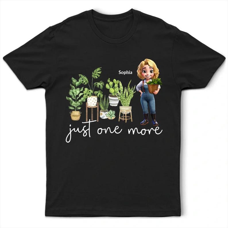 Puede incluir: Camiseta negra con una ilustraci&oacute;n de dibujos animados de plantas en macetas y una mujer sosteniendo una cesta de vegetaci&oacute;n. El texto "just one more" est&aacute; escrito en cursiva. El nombre "Sophia" est&aacute; encima de la mujer.