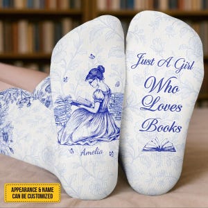 May include: White socks with a blue floral design and a sketch of a woman reading. The socks have the text "Just A Girl Who Loves Books" and the name "Amelia".