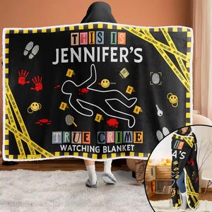 Könnte beinhalten: Schwarze Kapuzen-Decke mit einem Tatort-Design. Die Decke zeigt den Text "THIS IS JENNIFER'S TRUE CRIME WATCHING BLANKET" mit Tatortband, einer Körperumrisszeichnung und anderen Tatortelementen.