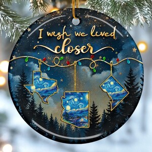 May include: Round Christmas ornament with a night sky design and the text "I wish we lived closer." The ornament features outlines of Texas, Arizona, and Washington D.C., each filled with a starry night painting.