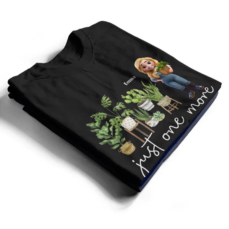 Puede incluir: Camiseta negra con una ilustraci&oacute;n de dibujos animados de un jardinero y plantas, con el texto "just one more". El jardinero sostiene una planta en maceta. El nombre "Emma" est&aacute; impreso encima de la ilustraci&oacute;n.