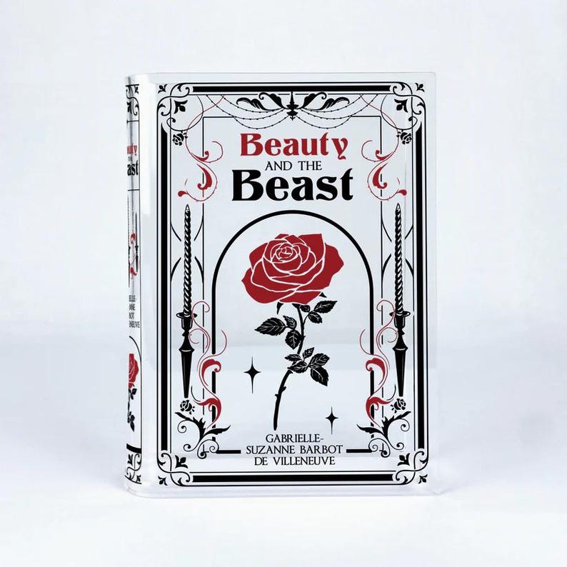 K&ouml;nnte beinhalten: Ein schwarzer und wei&szlig;er Buchumschlag mit einer roten Rose und dem Titel "Die Sch&ouml;ne und das Biest". Der Name des Autors ist Gabrielle-Suzanne Barbot de Villeneuve.