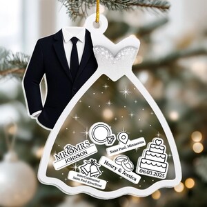 May include: A white wedding ornament featuring a tuxedo and a bridal gown silhouette. The ornament includes text that reads "MR & MRS JOHNSON", "Saint Paul, Minnesota", "Henry & Jessica", "06.03.2025", and "InterContinental Saint Paul Riverfront".