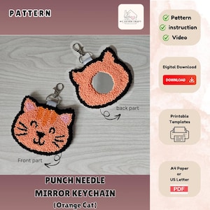 May include: A punch needle mirror keychain with an orange cat design. The keychain is made of yarn and has a mirror in the back. The front of the keychain features a cute orange cat face with black eyes and a pink nose. The keychain is attached to a silver key ring.