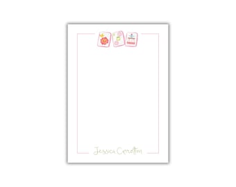 May include: A white notepad with a pink border and a green border. The top of the notepad has three pink squares with colorful designs. The bottom of the notepad has the text "Jessica Carrollton" in green.