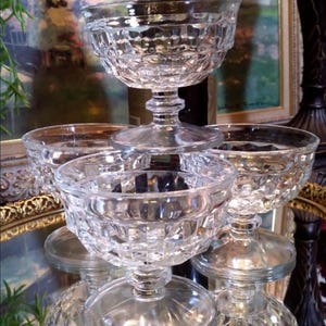 May include: A set of five clear glass dessert dishes with a diamond pattern. The dishes are stacked on top of each other, with the largest dish at the bottom and the smallest dish at the top.