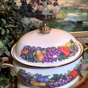 May include: White enamel pot with a gold lid and handles. The pot is decorated with a colorful fruit design featuring grapes, pears, and apples.