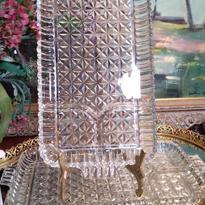 May include: A set of three clear glass serving trays with a diamond pattern. The trays are stacked on top of each other and have a decorative gold trim.
