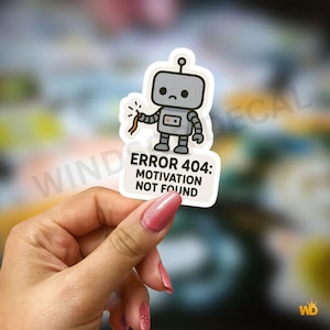 May include: A sticker depicting a grey cartoon robot with a dejected face, holding a broken wire. The text "ERROR 404: MOTIVATION NOT FOUND" is displayed on a white background. The sticker is a humorous design.