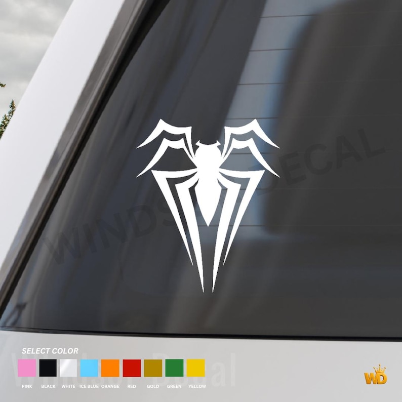 May include: White vinyl decal featuring a stylized spider design. The decal is applied to a car window. The image includes a color selection guide with options like pink, black, and gold. The decal is from WD.