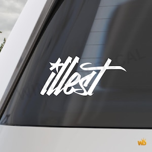 May include: White vinyl decal with the word "illest" in a stylized script font. The decal is applied to a car window, with the word in a bold, eye-catching design. The decal is a car accessory.