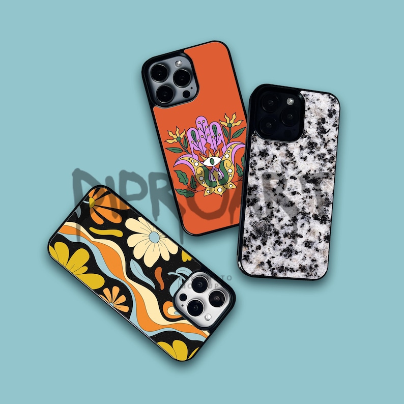 May include: Three different iPhone cases with unique designs. The first case is orange with a floral pattern and a purple hand with an eye. The second case is black with a white and gray marble pattern. The third case is black with a colorful abstract pattern.