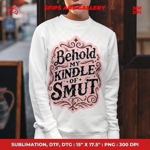 Puede incluir: Sudadera blanca con un gr&aacute;fico rosa y negro que dice "Behold My Kindle of Smut". El dise&ntilde;o est&aacute; enmarcado con adornos decorativos. La sudadera es de cuello redondo.