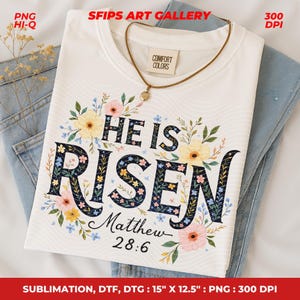 May include: A white t-shirt with the words "HE IS RISEN" in a floral design. The shirt also includes the text "Matthew 28:6". The shirt is approximately 15 inches by 12.5 inches.