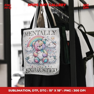 May include: White tote bag featuring a colorful illustration of a teddy bear sitting on clouds under a rainbow. The text "MENTALLY EXHAUSTED" is printed below the bear. The bag measures 15" x 18".
