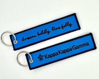 May include: Two blue keychains with black trim. One keychain has the text "dream boldly live fully" and the other has the text "Kappa Kappa Gamma".