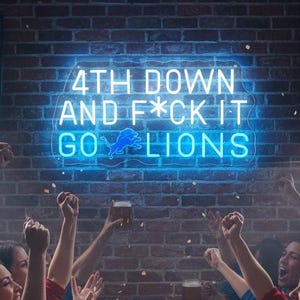 Peut inclure: Ambiance de bar sportif avec des fans enthousiastes regardant un match de football. Une enseigne au néon sur un mur de briques affiche "4th Down and F*ck It Go Lions." Bières et collations sur les tables. Ambiance festive.