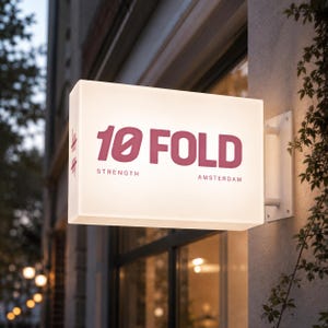 K&ouml;nnte beinhalten: Ein rechteckiges, beleuchtetes Wand-Schild mit einer wei&szlig;en, durchscheinenden Oberfl&auml;che. Das Schild zeigt den dunkelrosa Schriftzug 10 FOLD, wobei das Wort STRENGTH links und AMSTERDAM rechts darunter in kleinerer Schriftart angebracht sind.