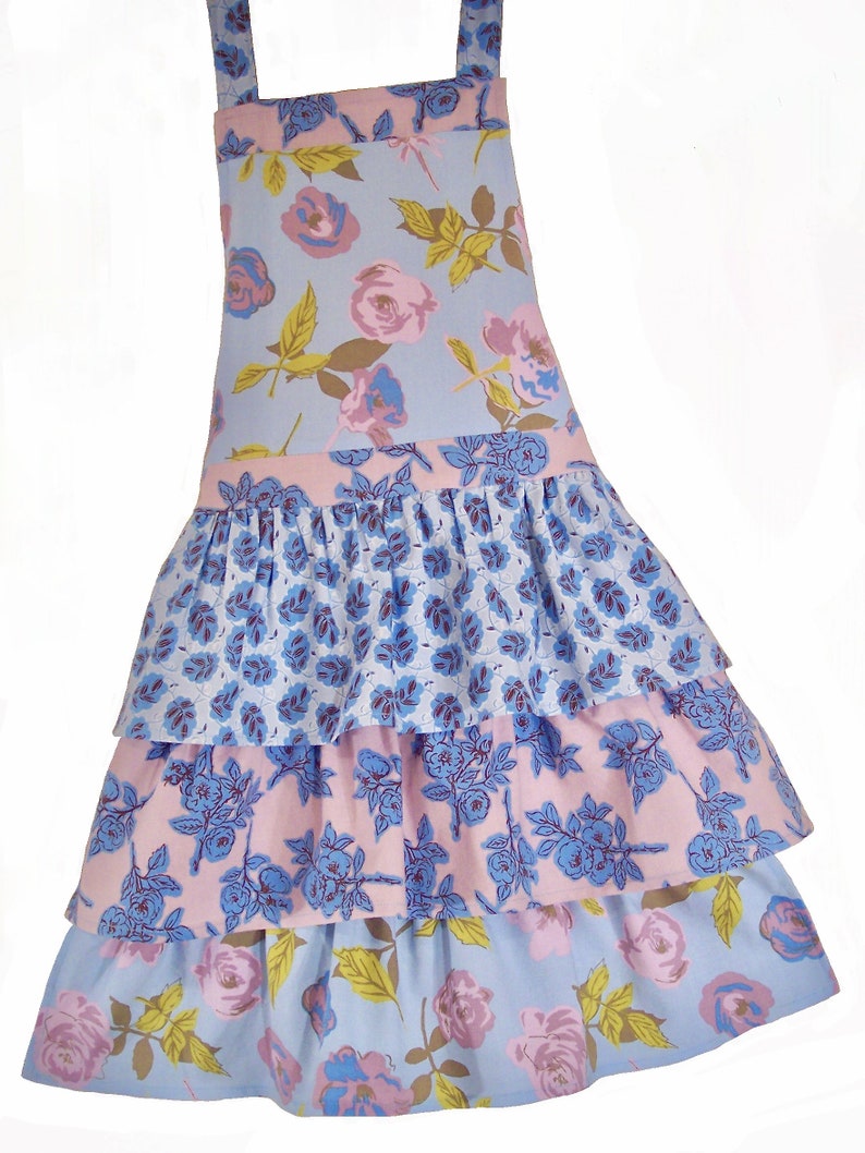 May include: A blue and pink floral print apron with a ruffled skirt. The apron has three tiers of ruffles and features a variety of floral patterns.