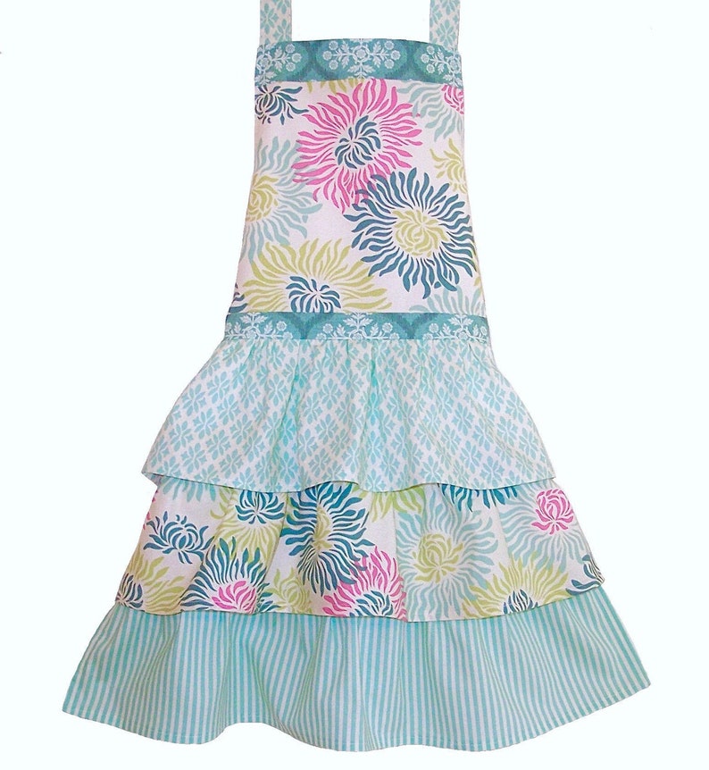 May include: A turquoise blue and white floral print apron with a ruffled skirt. The apron has three tiers of ruffles and a wide, floral print waistband.