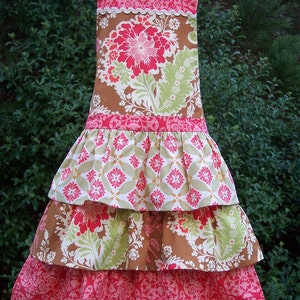 May include: A tiered apron with a brown and pink floral print. The apron has a ruffled bottom and a brown ribbon around the waist.