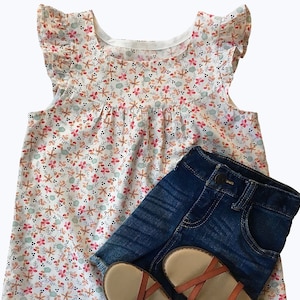 May include: A white sleeveless top with a floral print and ruffled sleeves. The top is paired with blue denim shorts and brown sandals.