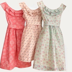 May include: Three vintage-style dresses in shades of coral, pink, and mint green. Each dress features a ruffled neckline, a fitted waist with a matching belt, and a flared skirt. The fabrics are patterned with floral or geometric designs.