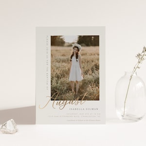 May include: A baptism invitation with a photo of a young girl in a white dress and a flower crown. The invitation is for August, Isabella Gilman, and includes the date, time, and location of the event.
