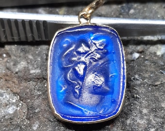 May include: A gold pendant with a blue glass cameo featuring a carved profile of a woman's face.