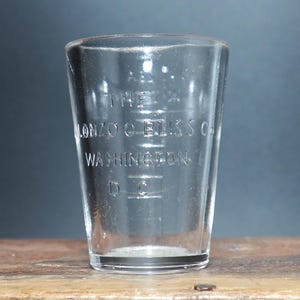 May include: A clear glass measuring cup with etched markings and the text "The Lonzo C. Bliss Co. Washington D.C."