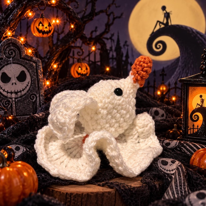 May include: A white crocheted ghost figure with a small orange nose and a single black eye. The ghost has a rounded head and a flowing, wavy base that mimics a sheet-like appearance, crafted with visible yarn stitches in a soft, textured pattern.