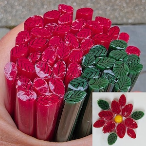May include: A bundle of cylindrical glass rods featuring a leaf pattern in red and dark green. The rods have a smooth, glossy finish. An inset image shows a flower arrangement created from these rods with red and green leaves and a yellow center.