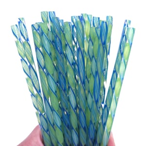 May include: A bundle of decorative glass straws with a spiral design. The straws feature a combination of blue and green hues, creating a visually appealing pattern. The straws are held together, showcasing their design and color variations.