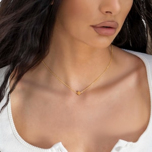 May include: A gold chain necklace with a small four-leaf clover pendant.