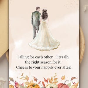 Op de afbeelding: Trouwkaart met een aquarel illustratie van een stel. De bruid draagt een witte jurk. Tekst luidt: "Falling for each other... literally the right season for it! Cheers to your happily ever after!" Herfstbladeren en pompoenen versieren de onderkant.