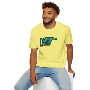 Puede incluir: Una camiseta amarilla con un gráfico de mano verde apuntando. La mano apunta hacia la derecha.