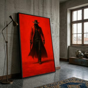 May include: A framed art print featuring a figure in a cowboy hat and long coat against a vibrant red background. The artwork depicts a mysterious character holding a gun, with a black frame. The print is leaning against a concrete wall.
