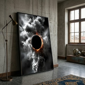 May include: A framed art print depicting a celestial event. The artwork features a black orb surrounded by swirling white and gray clouds with a fiery orange glow. The print is leaning against a concrete wall in a room with a window.