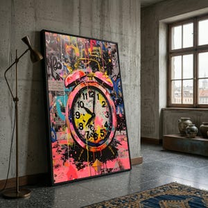 May include: A framed artwork featuring a vibrant, graffiti-style alarm clock design. The clock face is pink and yellow, with black hands pointing to 10:09. Splashes of pink, yellow, and blue paint cover the background, with graffiti-style lettering.